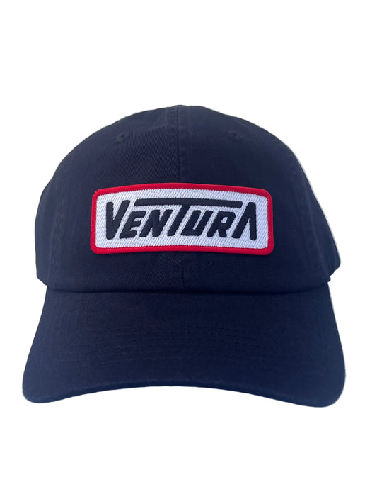 A black baseball cap featuring a rectangular embroidered patch on the front with the word 'VENTURA' in black on a white background, bordered in red.